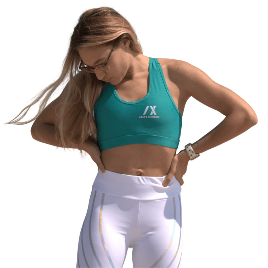 female athletic model posing for inspr exchange athletica while wearing teal green virago sport bra with white leggings
