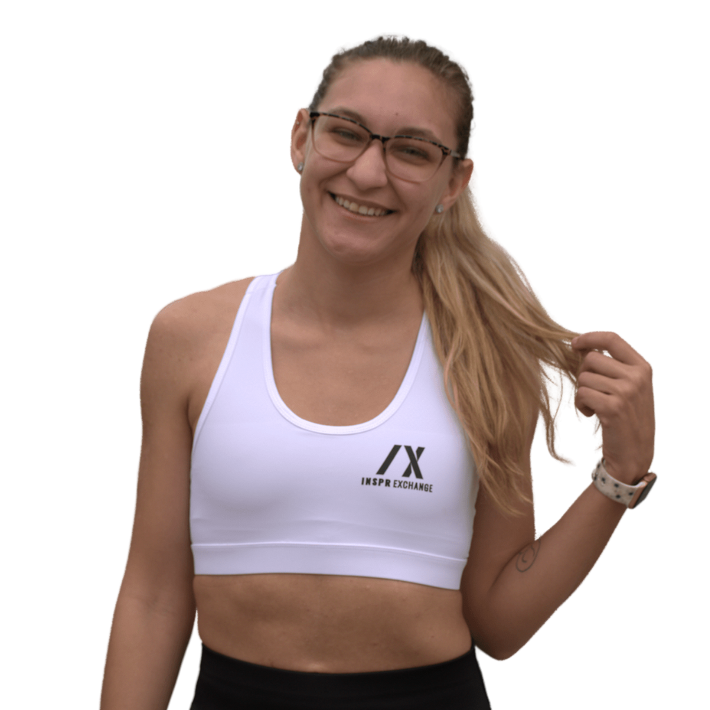 female athletic model posing for inspr exchange athletica while wearing white virago sport bra with black leggings